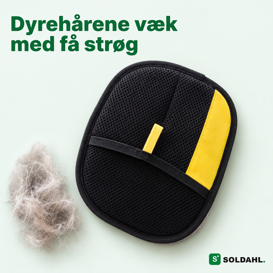 Soldahl kæledyrshårhandske med sort netlomme og gul flig ved siden af en totte kattehår