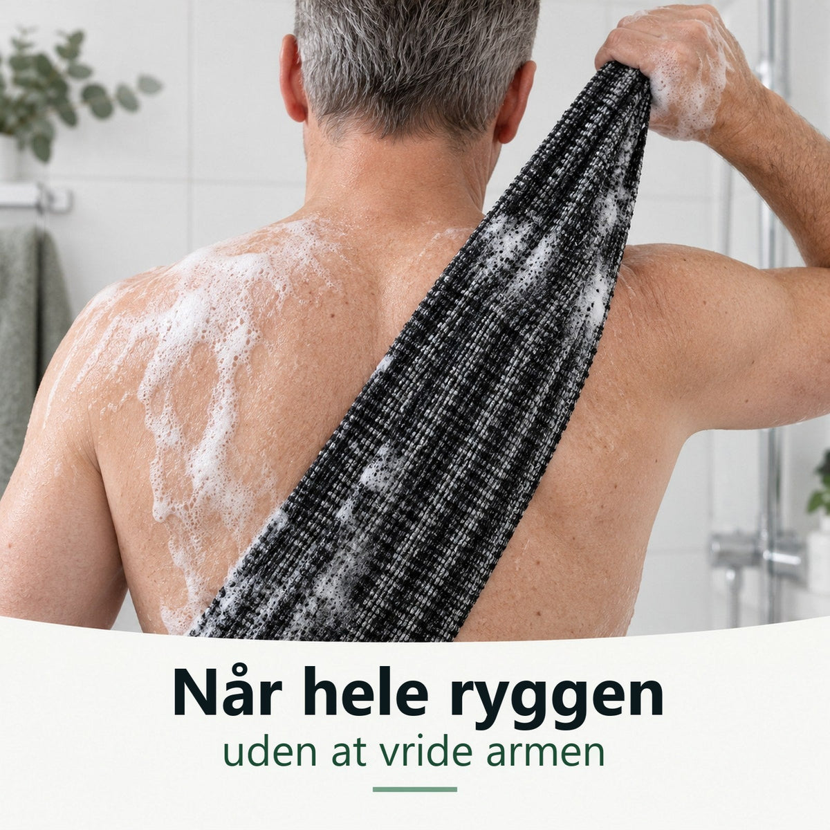 Mand skrubber den øverste del af ryggen med det lange skrubbehåndklæde i bruseren
