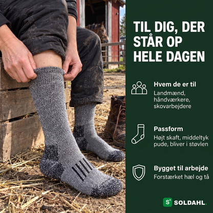 Kvinde tager grå arbejdsstrømpe på i en staldgård, til dig der står op hele dagen
