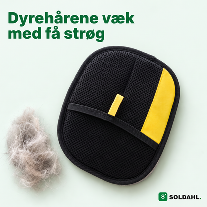 Soldahl kæledyrshårhandske med sort netlomme og gul flig ved siden af en totte kattehår