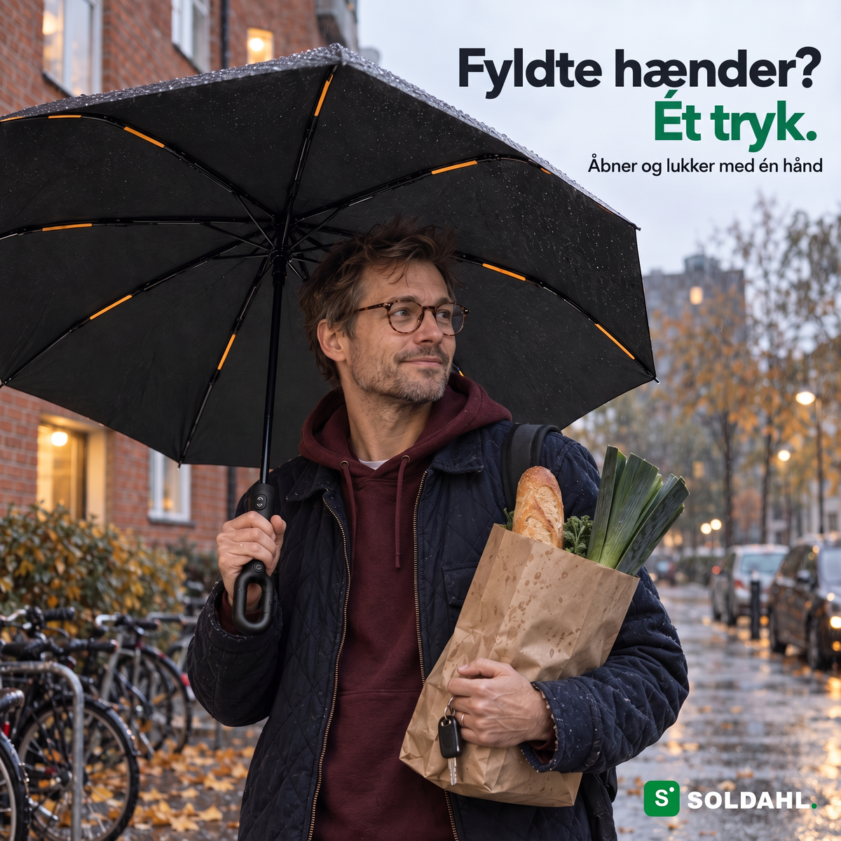 Mand med indkøbspose holder Stormparaplyet i ringhåndtaget med én hånd i regnen