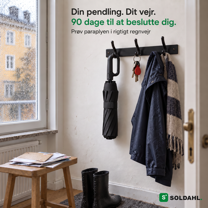 Sammenfoldet Stormparaply hænger i sit ringhåndtag på en knage i entreen