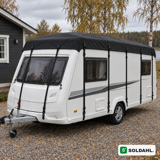 Sort tagbeskyttelse monteret på hvid campingvogn på grusindkørsel